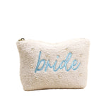 White fluffy pouch with 'bride' embroidered in blue on a beige background. Available at Be Charmed