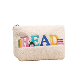 White fleece pouch with colorful 'READ' text on a beige background. Availablea at Be Charmed