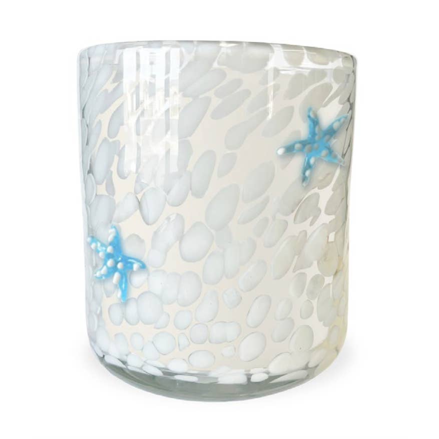 Glass candle holder with pebble pattern and blue starfish decorations on a white background. Available t Be Charmed