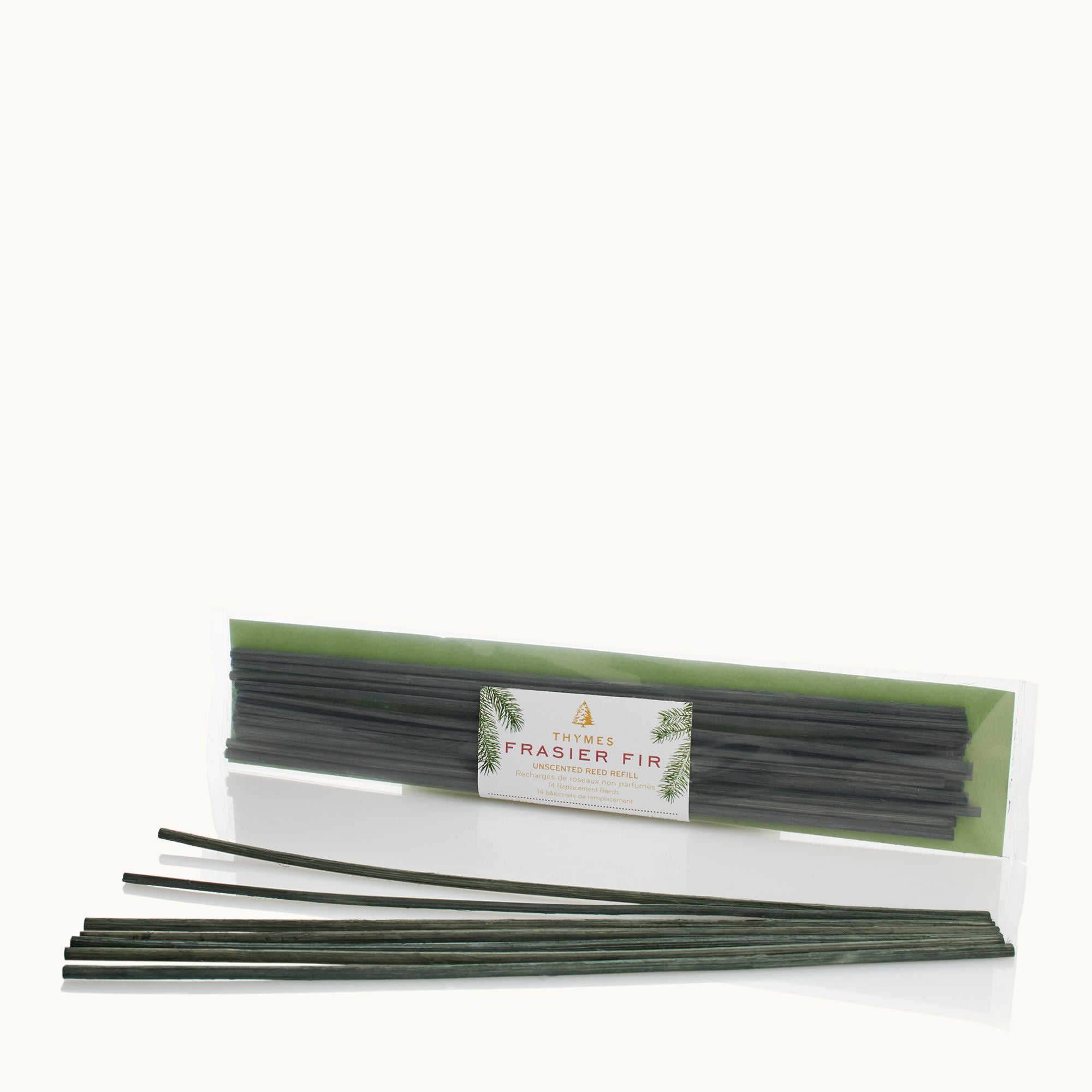 A package of Thymes Frasier Fir unscented reed refills, consisting of several dark green reeds in a clear packaging with a green label. Available at Be Charmed