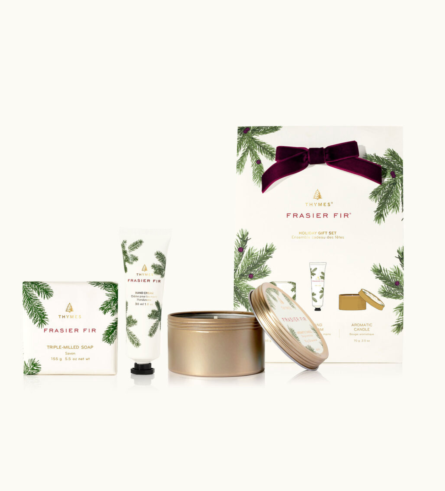 A Thymes Holiday Gift Set which includes a bar soap, petite hand cream, and a travel tin, all in Frasier Fir fragrance. The packaging is primarily white and green with a gold bow on top.