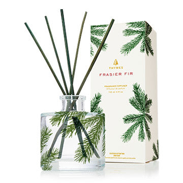 Thymes Frasier Fir Pine Needle Petite Reed Diffuser, with clear glass bottle and pine needle design, alongside its packaging box with matching design. Available at Be Charmed