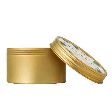 A gold travel tin candle with a lid, featuring a label with a Christmas tree and snowflake design. Available at Be Charmed