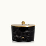 Black marbled candle jar with gold lid on a white background, featuring the Thymes logo. Available at Be Charmed.  