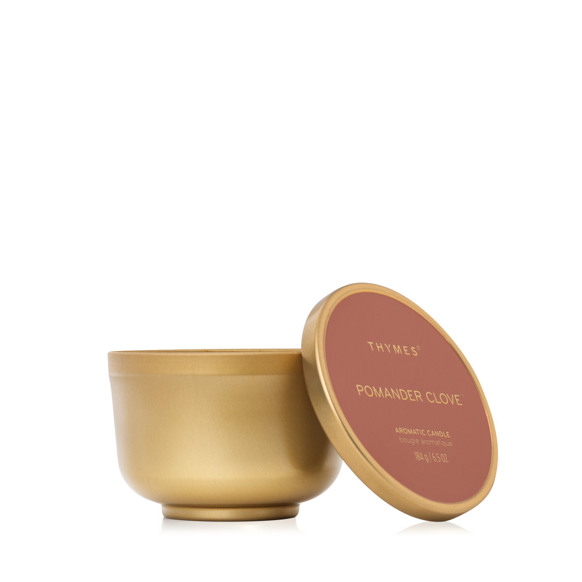 Gold candle jar with pink lid featuring 'Thymes' branding on a white background. Available at Be Charmed