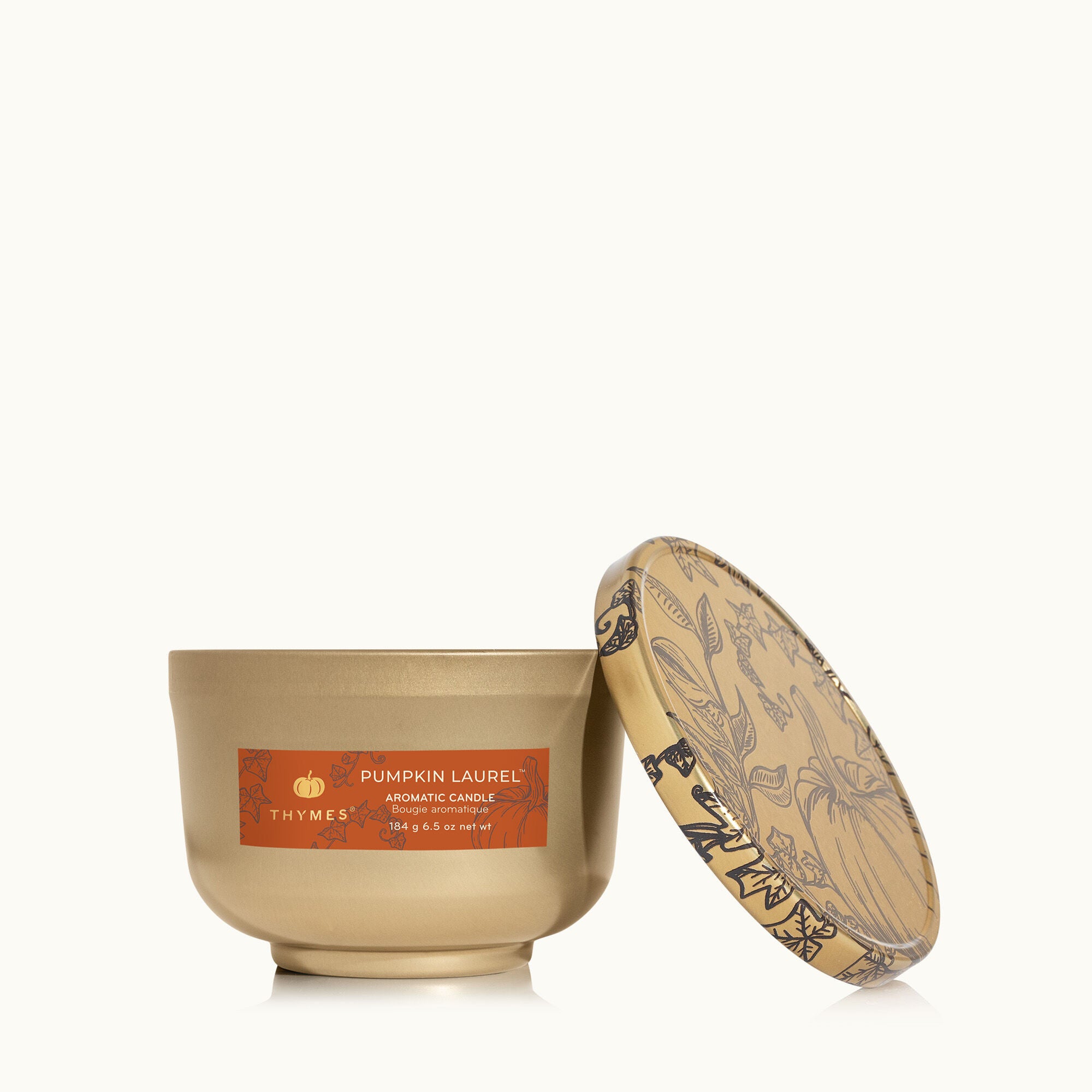 Thymes Pumpkin Laurel Poured Candle Tin w/Gold Lid in burnt‑orange metal tin with gold lid—warm fall spice scent of pumpkin, nutmeg & clove. Available at Be Charmed.