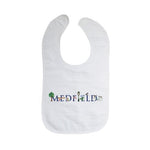 A white cotton bib with velcro closure, featuring the text 'MEDFIELD' and some decorative elements in blue and green. Available at Be Charmed