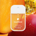 Touchland hand sanitizer bottle with a fruit-themed background. Available at Be Charmed