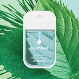 Touchland hand sanitizer packaging on a green leaf background. Available at Be Charmed