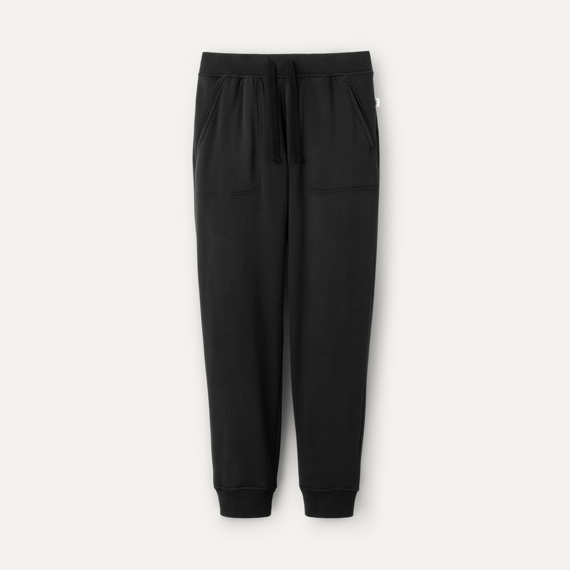 A pair of black UGG men's jogger pants with a drawstring waist and a brand tag on the lower left side. Available at Be Charmed