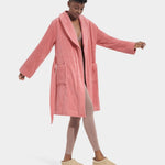 A model wearing a pink UGG Lenore Terry Robe with traditional patch pockets and an embroidered UGG heritage logo. Available at Be Charmed