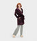 A woman standing and modeling a purple UGG robe with a neutral facial expression, wearing matching pants, with her hands in pockets. Available at Be Charmed