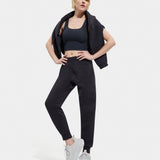 A female model standing, posing, and turning to face the camera. She is wearing a black UGG Ink Sofiana Mixed Jogger with an elastic waistband, and white sneakers. Available at Be Charmed