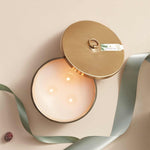 View of lit Thymes Frasier Fir Frosted Plaid 3-Wick Candle with festive holiday scent – Available at Be Charmed