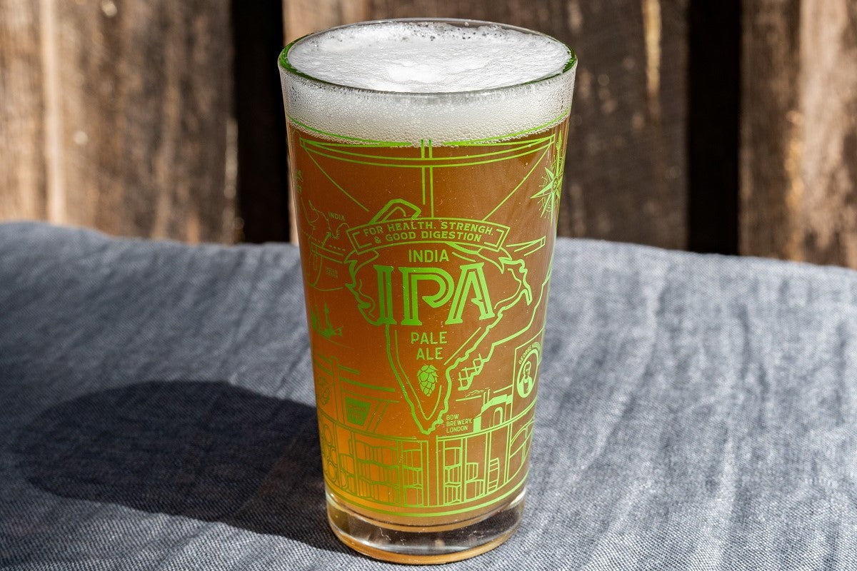 Glass of IPA beer with foam on a wooden surface. Available at Be Charmed