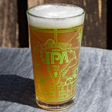 Glass of IPA beer with foam on a wooden surface. Available at Be Charmed