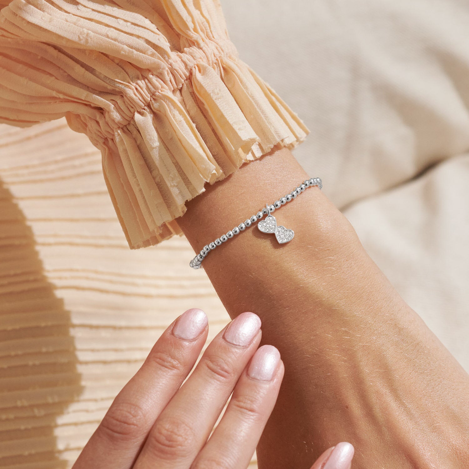 Woman Wearing A Littles & Co Silver Confetti Friendship Bracelet—shimmering silver bracelet with heartfelt charm, perfect gift for friends from Be Charmed.