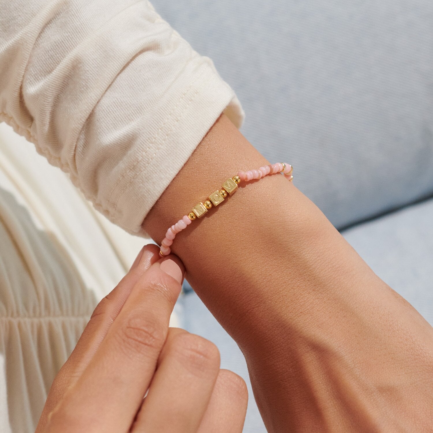 Close-up of a wrist wearing a pink beaded bracelet with gold accents. Available at Be Charmed