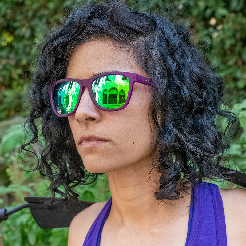 Woman wearing Goodr Gardening With a Kraken Sunglasses featuring polarized lenses and a vibrant purple-and-teal design, perfect for sunny days in the garden or outdoors, available at Be Charmed