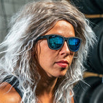 Woman wearing Goodr Mick & Keith's Midnight Ramble Sunglasses featuring classic black frames and blue smoke-tinted polarized lenses, designed for high-energy adventures and effortless cool, available at Be Charmed