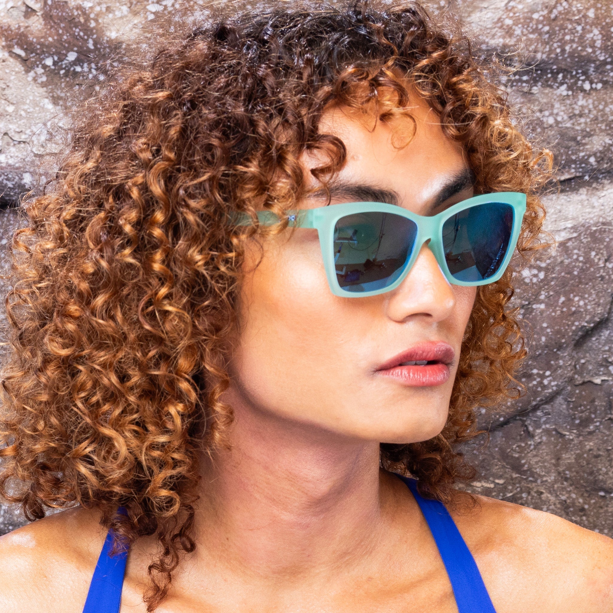 Woman wearing Goodr Will Brake For Mermaids Sunglasses with ttranslucent teal frames and reflective tealpolarized lenses, combining playful ocean vibes and performance fit, available at Be Charmed