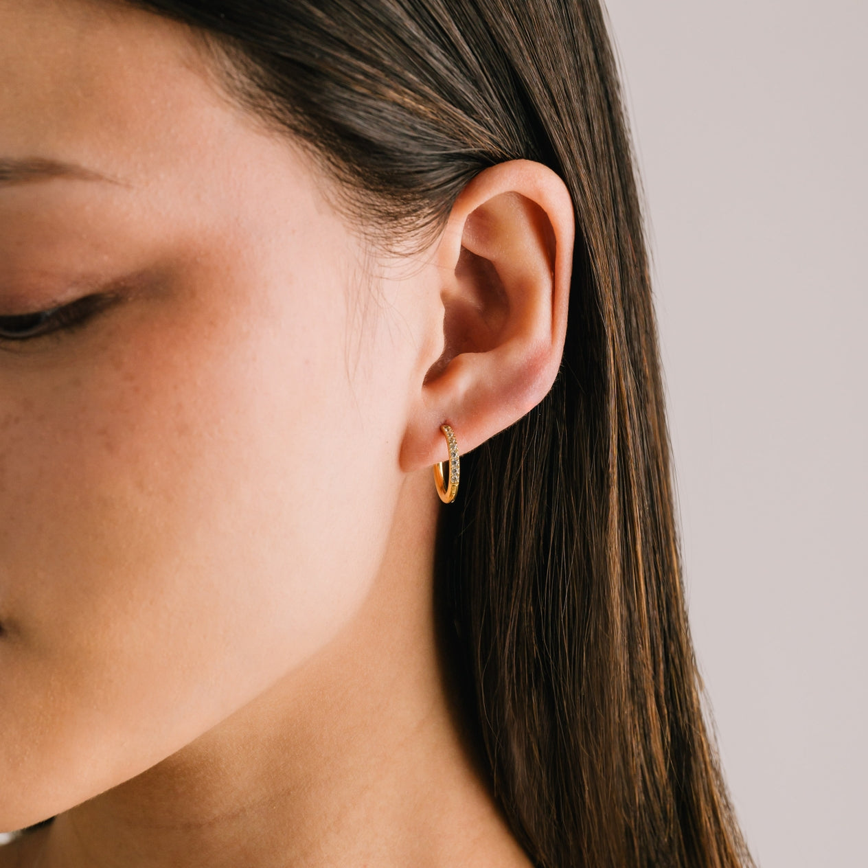 Woman wearing Lover's Tempo Evie 15mm gold hoop earrings with sleek finish, available at Be Charmed.