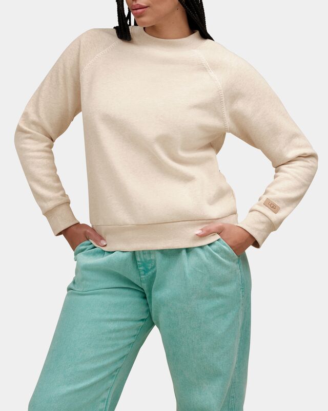 Person wearing a beige sweater and teal pants on a white background. Available at Be Charmed
