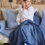 Woman with Chappy Wrap Harborview Herringbone Blanket on lap – Original size throw in a classic light grey herringbone pattern. Plush, durable, and machine washable. A cozy neutral accent for the home or perfect gift. Available at Be Charmed.