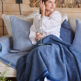 Woman with Chappy Wrap Harborview Herringbone Blanket on lap – Original size throw in a classic light grey herringbone pattern. Plush, durable, and machine washable. A cozy neutral accent for the home or perfect gift. Available at Be Charmed.