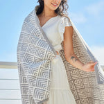 Woman wrapped in Oyster Cove Grey ChappyWrap Blanket featuring a classic diamond weave pattern, made from a cotton-blend fabric for exceptional softness and durability—ideal for cozy nights or elegant home décor. Available at Be Charmed.