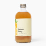 Bottle of Lemon Drop syrup with a label on a white background. Available at Be Charmed