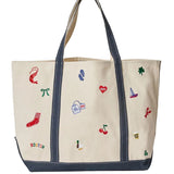 An Alice & Wonder canvas tote bag with dark navy blue trim, handles, and bottom panel, decorated with colorful embroidered motifs including a red sock, cherries, a clover, and a small sailboat. The word 'BOSTON' is embroidered in multicolor letters near the bottom left. Available at Be Charmed