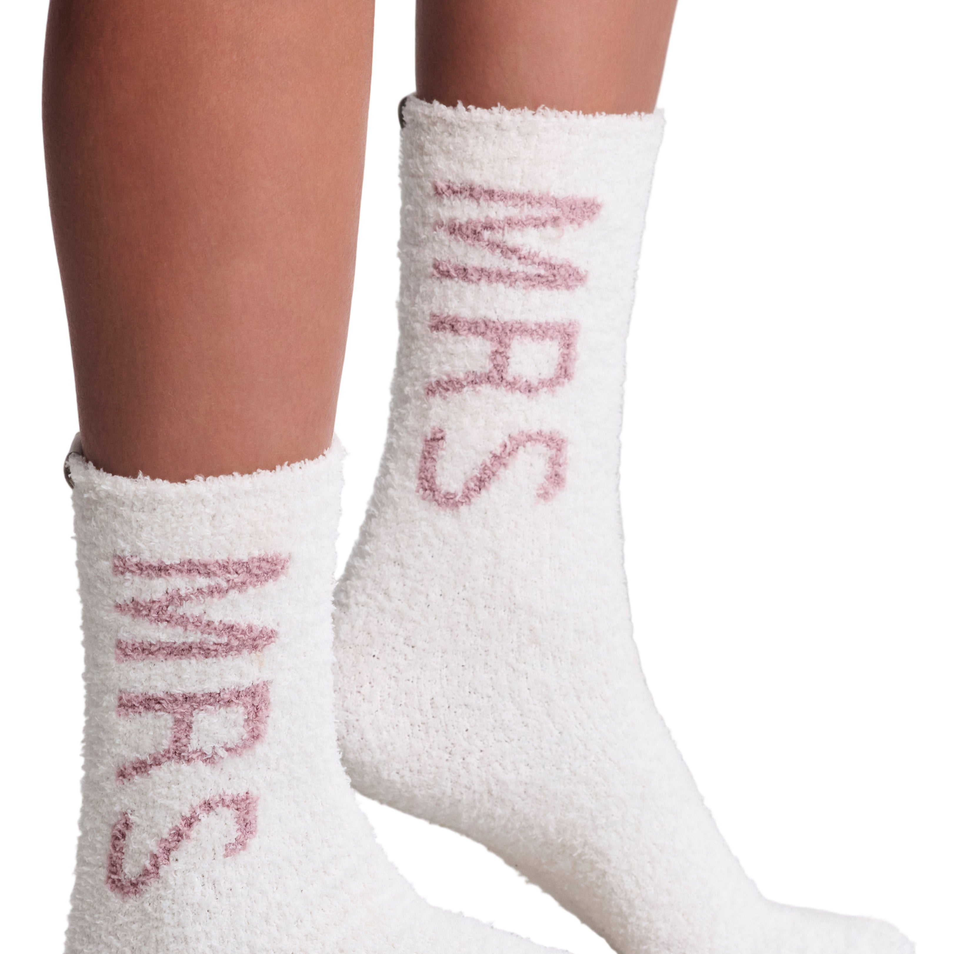 White fuzzy socks with pink Mrs text worn by a person on a light gray background. Mrs Wedding fuzzy socks. Available at Be Charmed. 