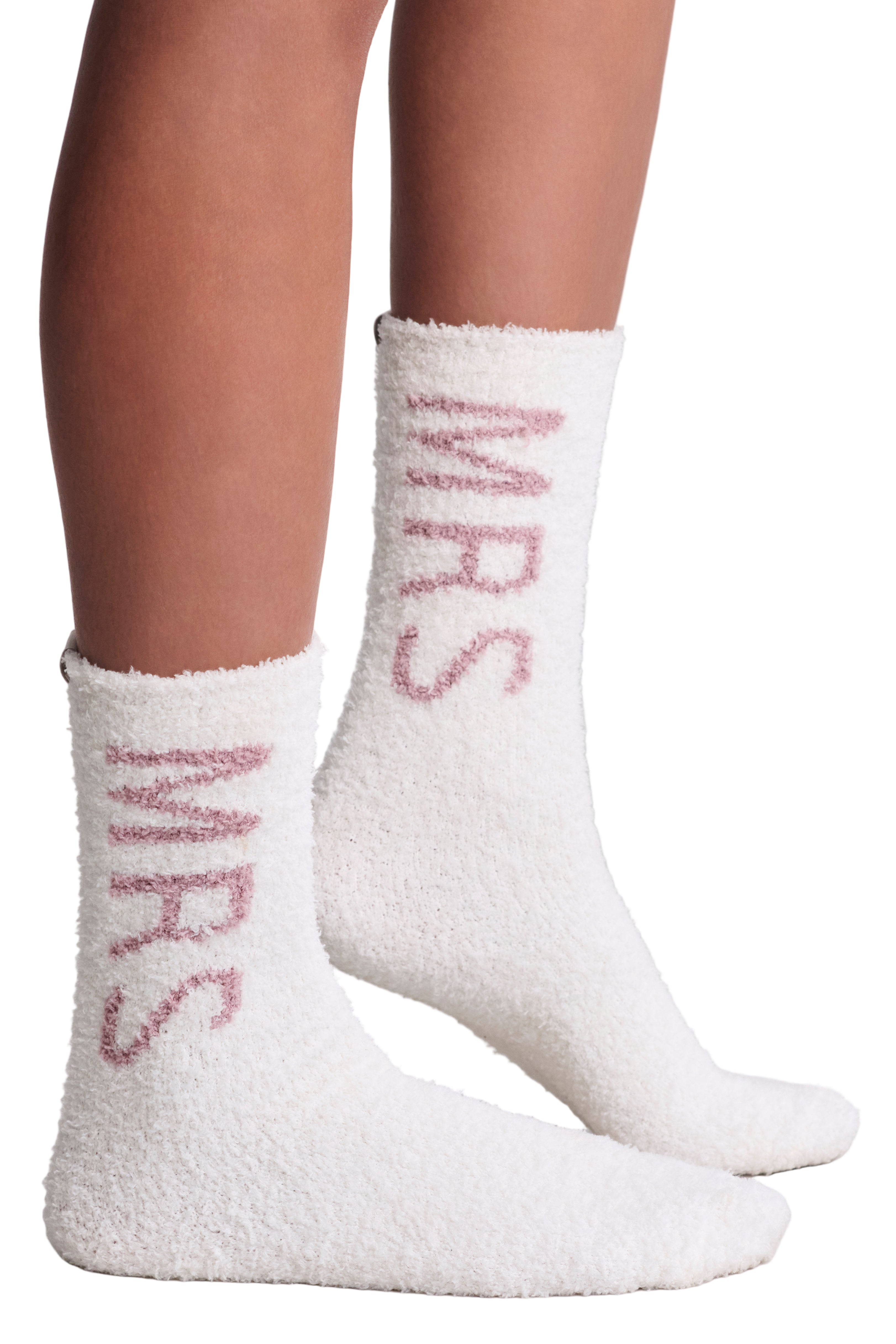 White fuzzy socks with pink Mrs text worn by a person on a light gray background. Mrs Wedding fuzzy socks. Available at Be Charmed. 