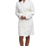 A woman modeling a pearl Barefoot Dreams  textured waffle-knit bathrobe against a white studio background.