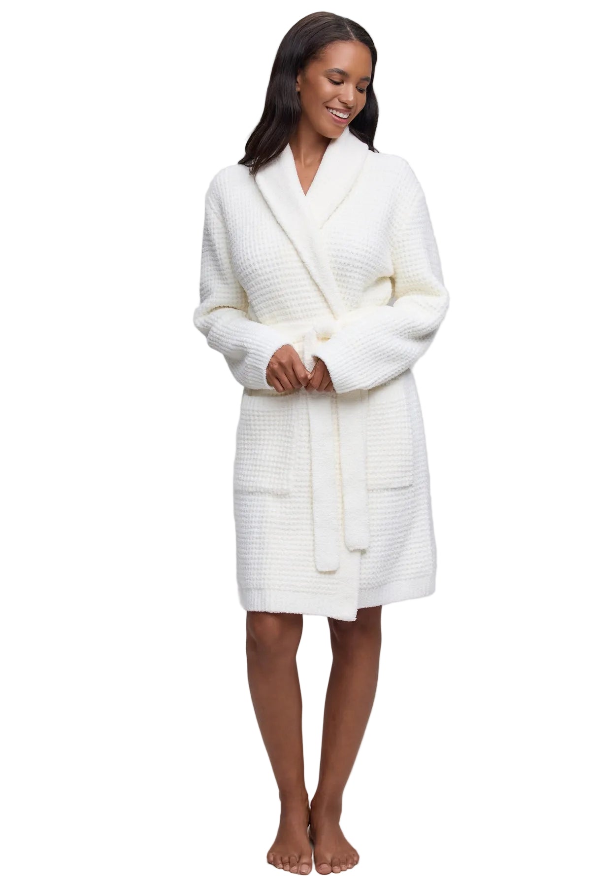 A woman modeling a pearl Barefoot Dreams  textured waffle-knit bathrobe against a white studio background.