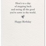 Inside reads “Here’s to a day of stepping back and seeing all the good you’ve sown in the world.” with a small heart and “Happy Birthday.” Available at Be Charmed.