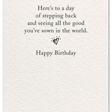 Inside reads “Here’s to a day of stepping back and seeing all the good you’ve sown in the world.” with a small heart and “Happy Birthday.” Available at Be Charmed.