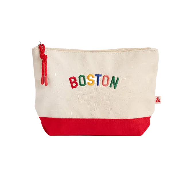An off-white canvas zippered pouch with a red bottom panel and a colorful 'BOSTON' text logo on the front, set against a light gray background. Available at Be Charmed