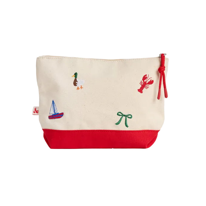 A canvas zippered pouch with a cream upper section and a red bottom base, decorated with small embroidered nautical and abstract motifs including a sailboat, lobster, and green symbol. It features a red drawstring zipper pull on a white background. Available at Be Charmed