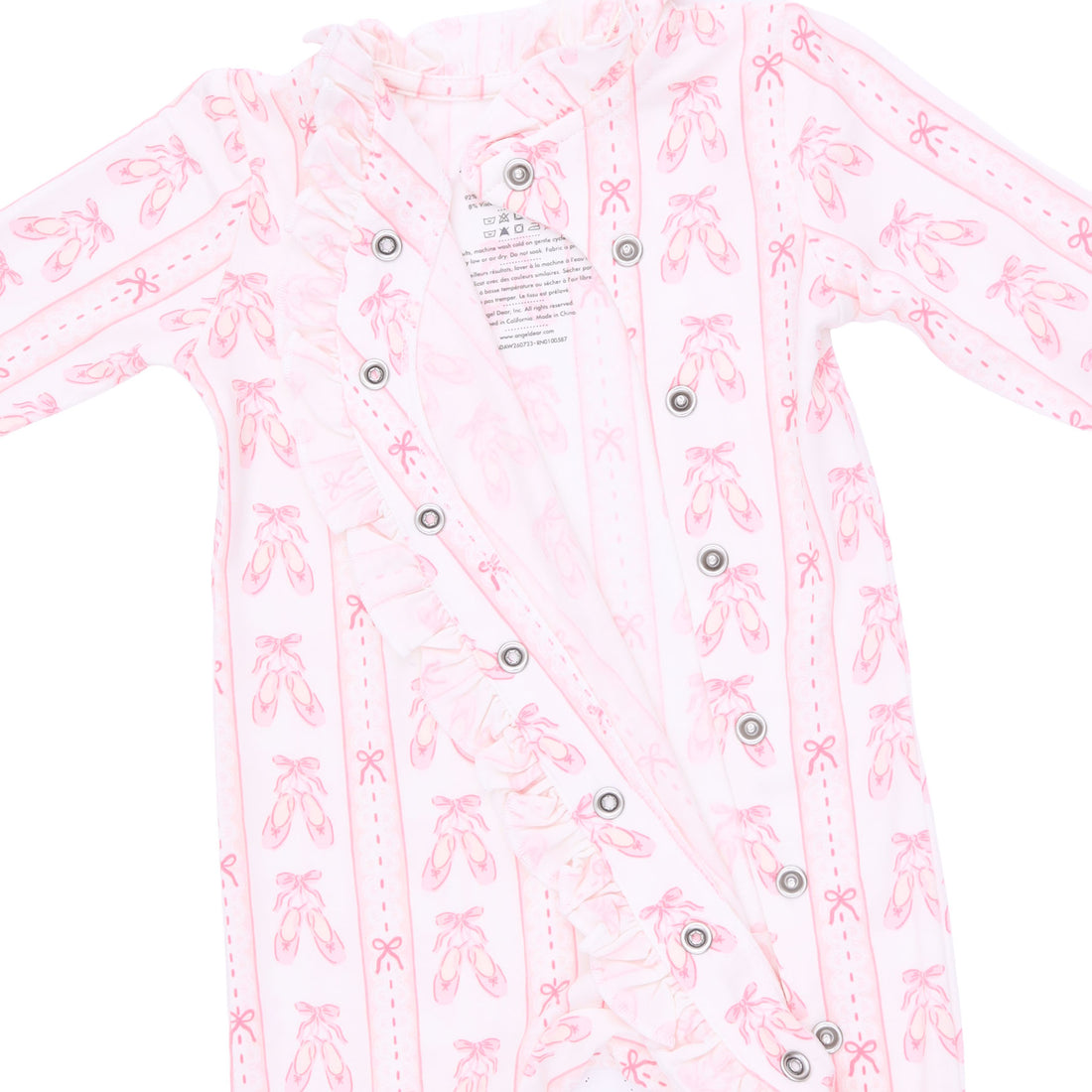 A long-sleeve baby romper in light pink with a repeating ballet shoe print, featuring a ruffled collar and snap-button front closure. Available at Be Charmed