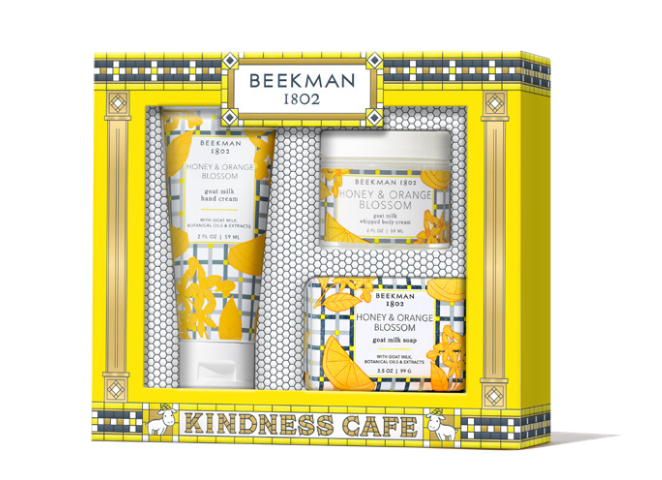 Beekman 1802 Kindness Cafe gift set containing goat milk hand cream, whipped body cream, and honey & orange blossom soap in a yellow and gray patterned box. Available at Be Charmed