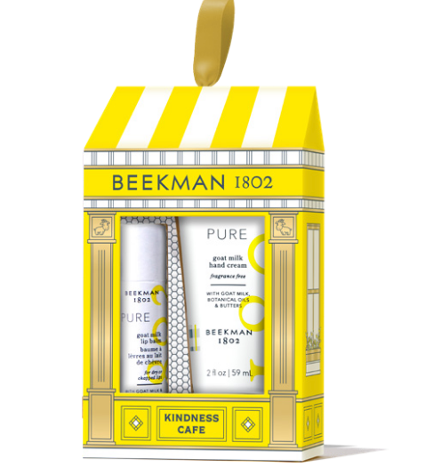 Beeckman 1802 Kindness Cafe gift set containing a goat milk hand cream and hand wash, presented in a yellow and white storefront-style box with a hanging loop. Available at Be Charmed
