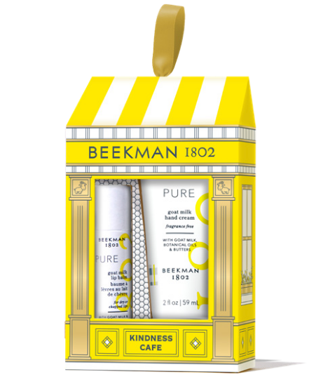 Beeckman 1802 Kindness Cafe gift set containing a goat milk hand cream and hand wash, presented in a yellow and white storefront-style box with a hanging loop. Available at Be Charmed