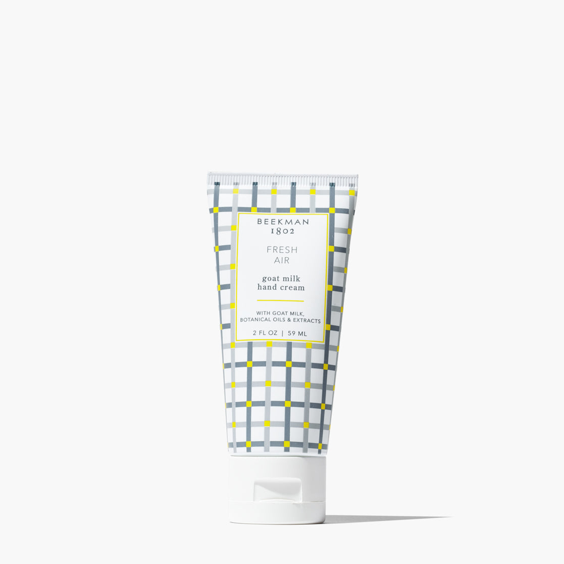 A squeeze tube of Beerman 1853 Fresh Air goat milk hand cream, featuring a white and gray plaid pattern with yellow accents, on a clean white background. Available at Be Charmed