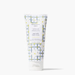 A squeeze tube of Beekman 1802 Vanilla Absolute goat milk hand cream, featuring a white and gray patterned design with yellow accents and white floral illustrations, set against a clean white background. Available at Be Charmed