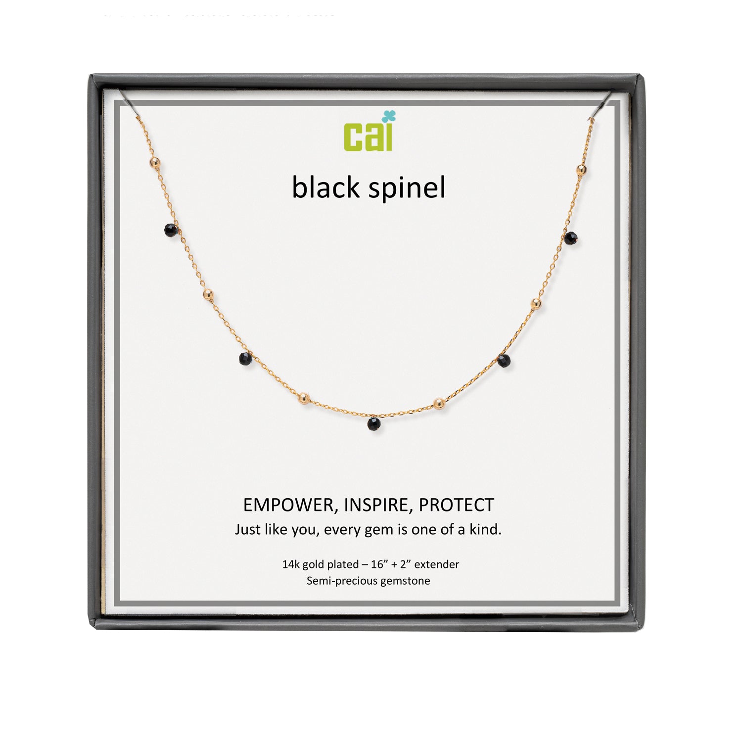 A CAI gold-plated necklace with small black gemstone beads displayed on a white card inside a black gift box. The card shows the brand name 'cai' and the text 'black spinel'. Available at Be Charmed