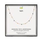 A CAI gold-plated lapis necklace with small blue gemstones, presented in a square black gift box with a white insert card. The card features the brand logo 'cai' and the word 'lapis' along with a quote. Available at Be Charmed