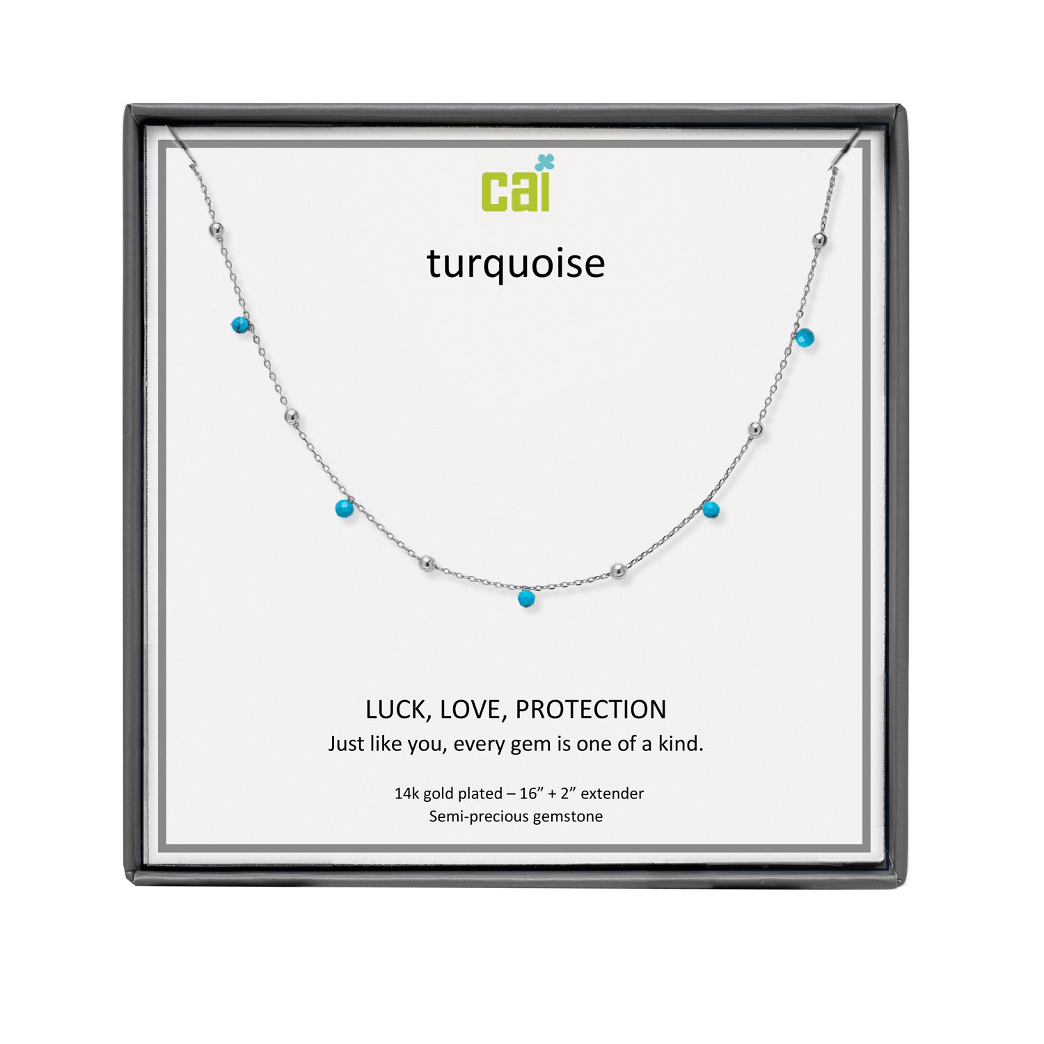 A CAI silver-toned necklace with small turquoise gemstones displayed on a white presentation card inside a black gift box. The card shows the brand name 'cai' and the word 'turquoise', along with the text 'LUCK, LOVE, PROTECTION'. Available at Be Charmed