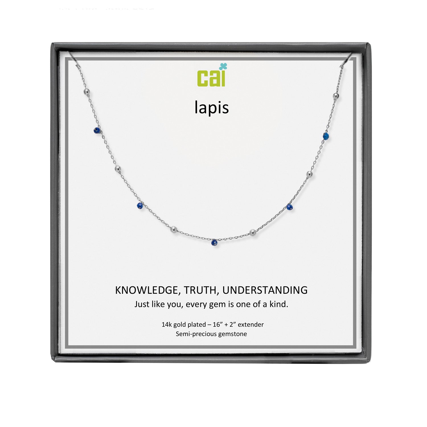 A CAI silver necklace with small blue and clear gemstones displayed on a white card inside a square black gift box. The card is branded with the logo 'cai' and the word 'lapis'. Available at Be Charmed
